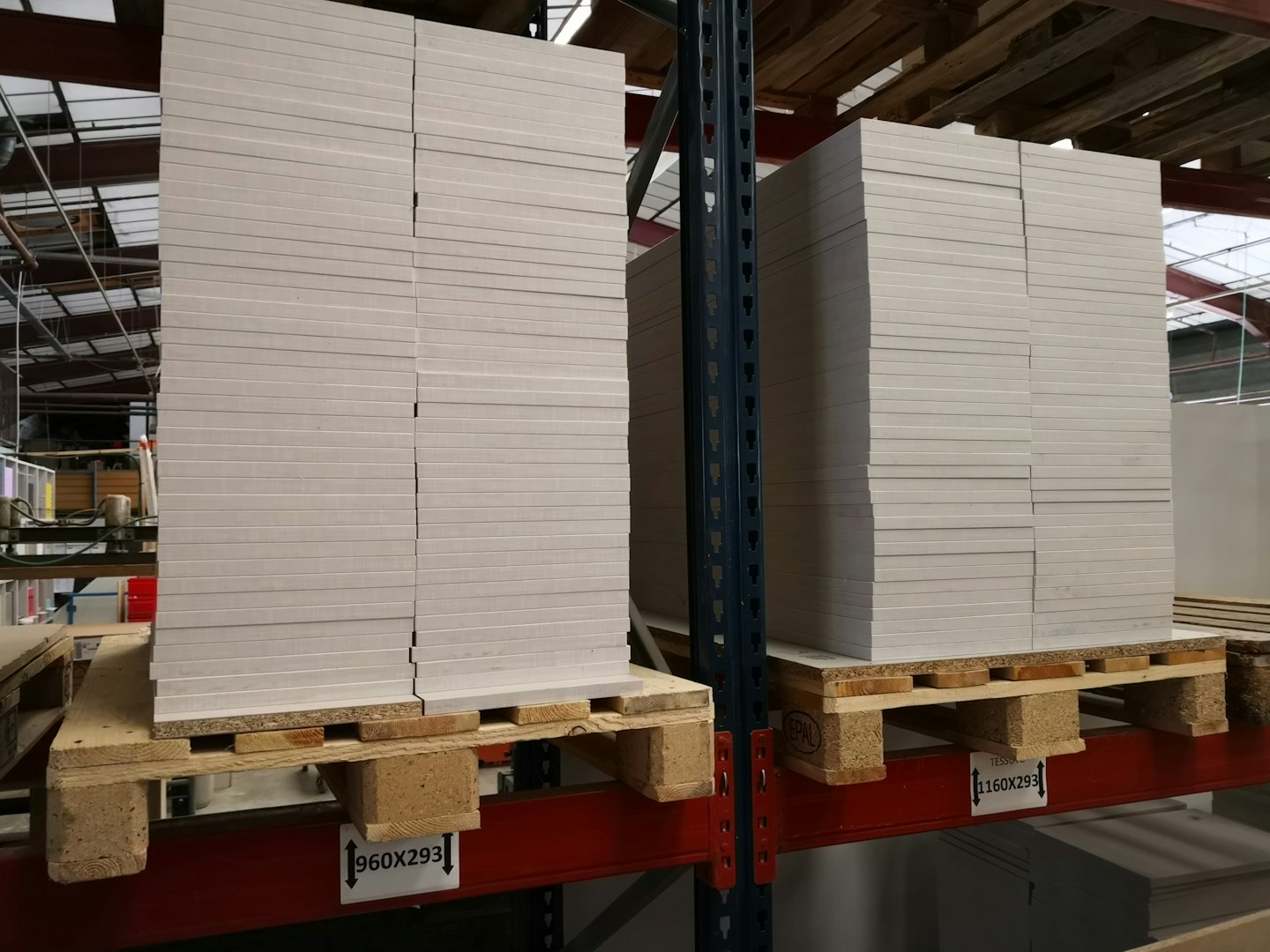 Paneles rectangulares apilados en estanterías industriales en un almacén.