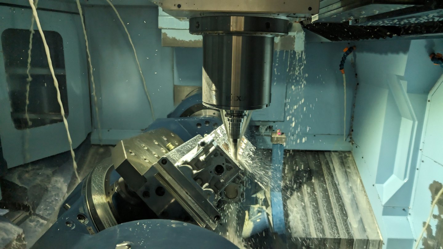 Máquina fresadora CNC rocía refrigerante sobre pieza de metal.